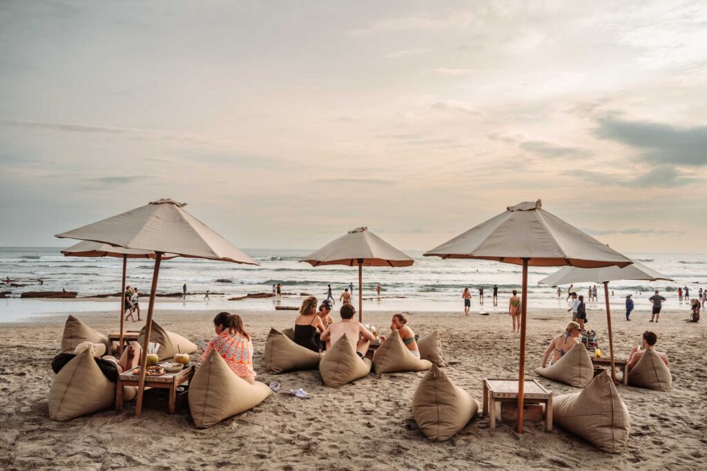 Crowded beach in Canggu during peak season showing surfers and beachgoers